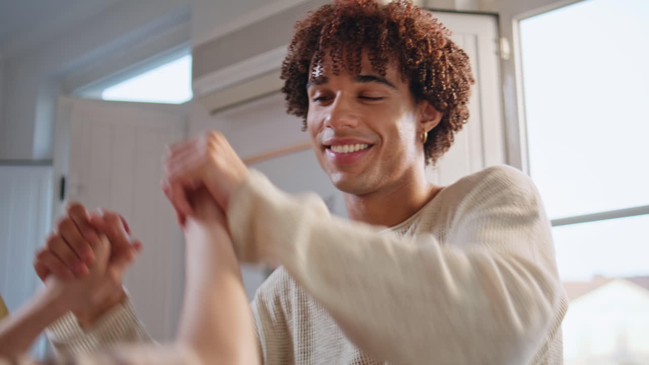 Relaxed couple enjoy disco party dancing with friends at light apartment closeup