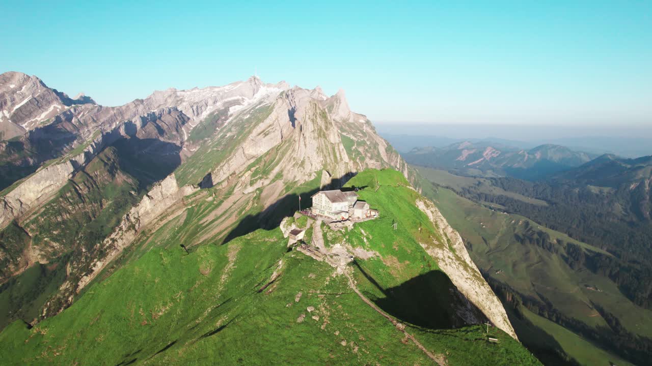 Yeşil bir sırtta Schaeffler Kulübesi Alp dağ evinin havadan drone görüntüsü, İsviçre Alpleri yürüyüş destinasyonu, dramatik zirveler, yazlık Alp manzarası, İsviçre'nin doğal güzelliklerini gösteren seyahat turizmi çekimleri
