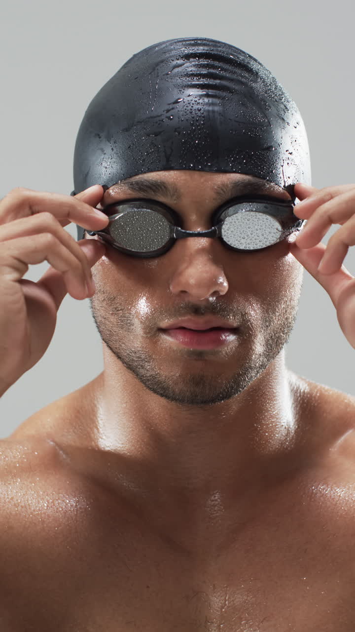Vertical video: Adjusting swimming goggles, male swimmer preparing for competition, wearing swim cap