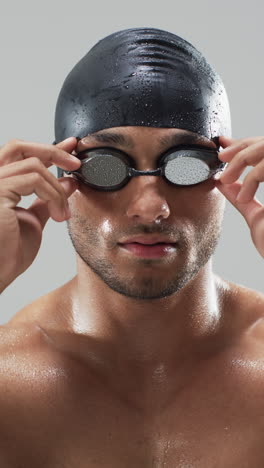 vertical video: adjusting swimming goggles, male swimmer preparing for competition, wearing swim cap