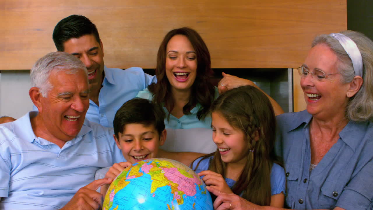 Família estendida olhando para um globo juntos no sofá