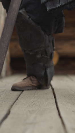 knight walks on wooden bridge leaning on spear heavily. strong medieval warrior prepares for duel in ancient village closeup on blurred background