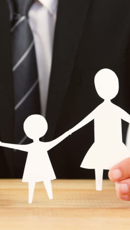 businessman holding a paper cut out of family