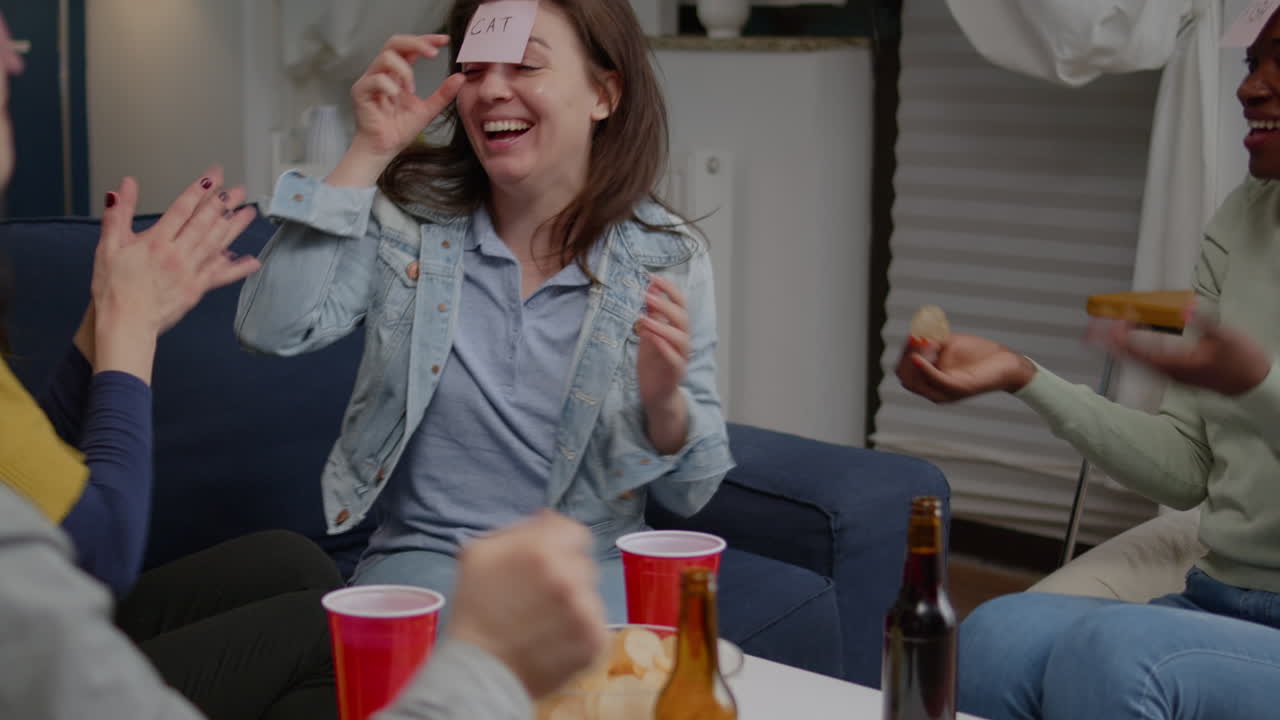 혼성 인종 친구들이 거실에서 모여 짐작하세요 누가 게임을 하고 있습니다.