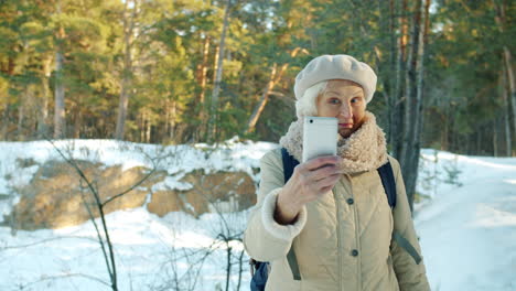 senior woman taking a selfie in a snowy forest