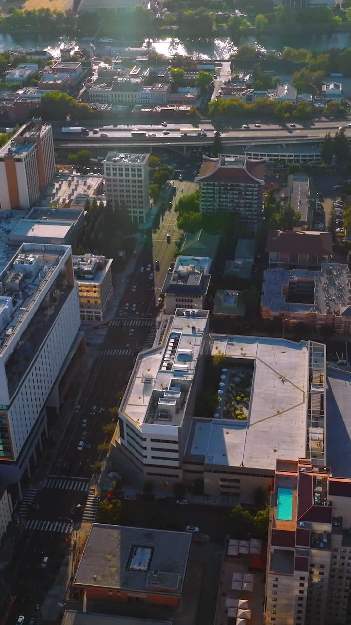 Flying over the busy streets of lively Sacramento at daytime. Sacramento River at backdrop. Top view. Vertical video