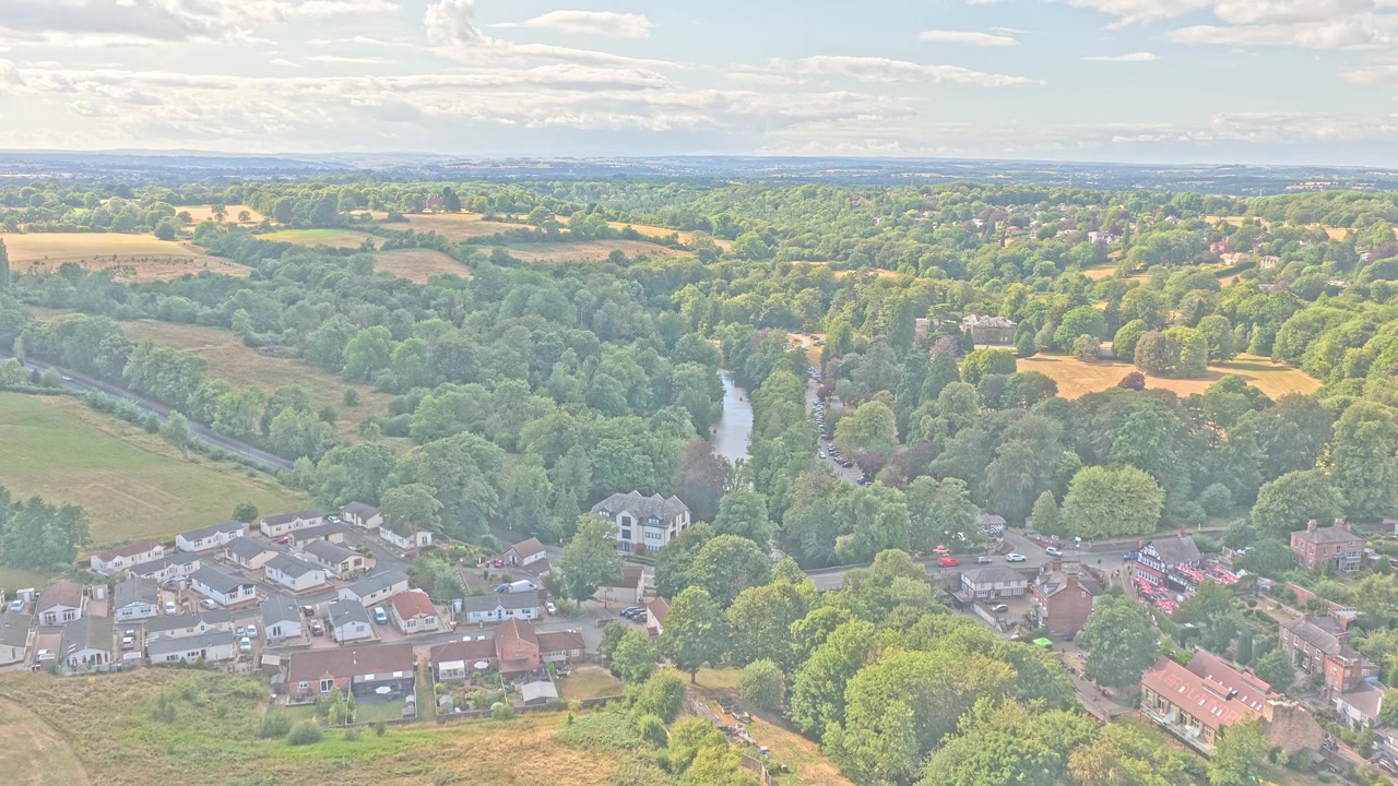 O rio Nidd serpenteia por vales arborizados, terras agrícolas e o histórico povoado de Knaresborough, North Yorkshire, Inglaterra, Reino Unido, sobrevoo frontal com drone