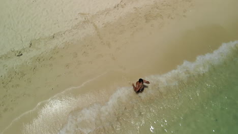 Top-view-of-a-man-walking-towards-the-ocean-for-a-swim