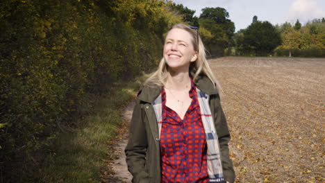 a woman walking through a field in autumn