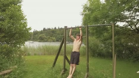 athletic young man doing pullups on outdoor home gym slow-motion