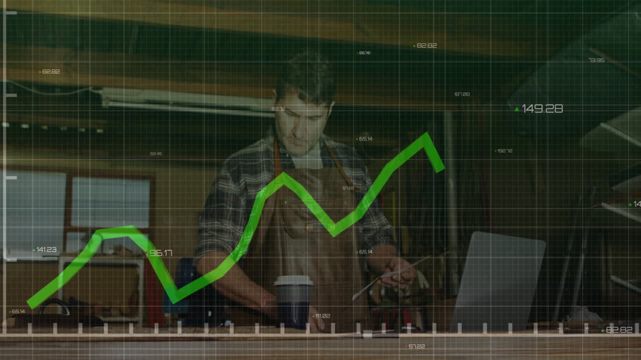 Male craftsman examining tablet at workbench, overlaying live financial line graph metrics