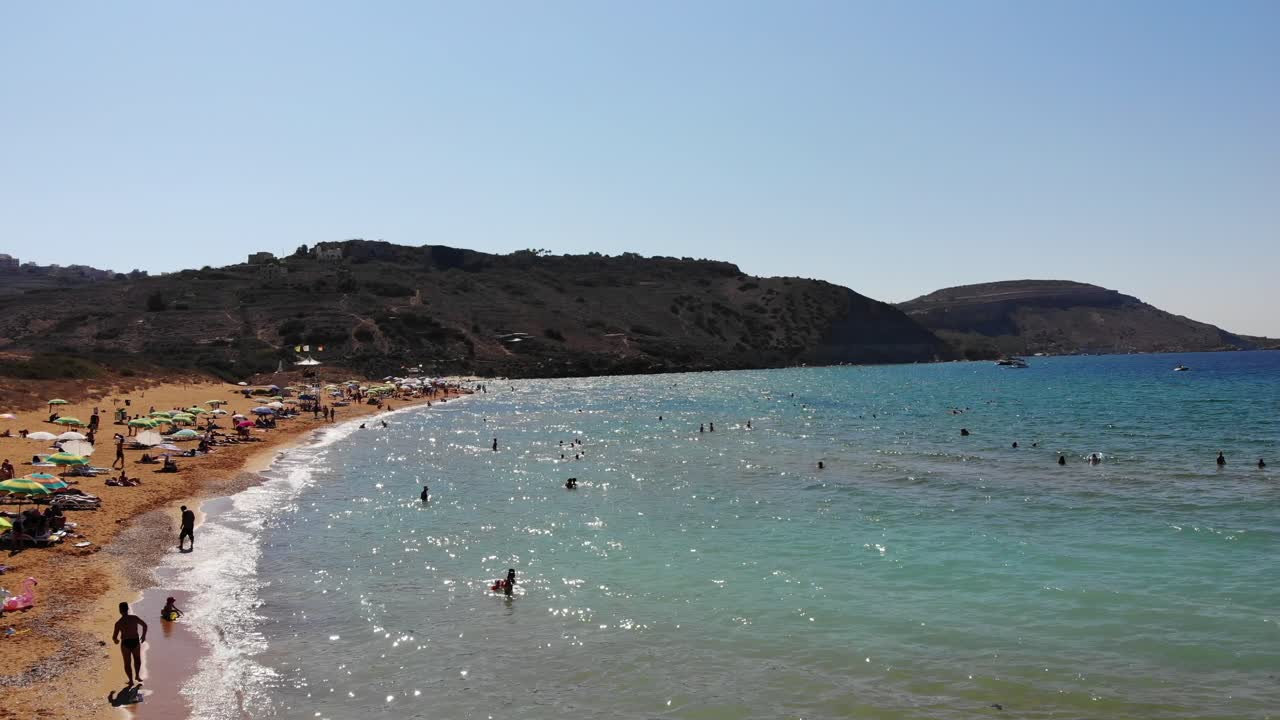 享受地中海夏季假期的人在戈佐拉姆拉湾,马耳他岛在蓝海旁边的炎热日子