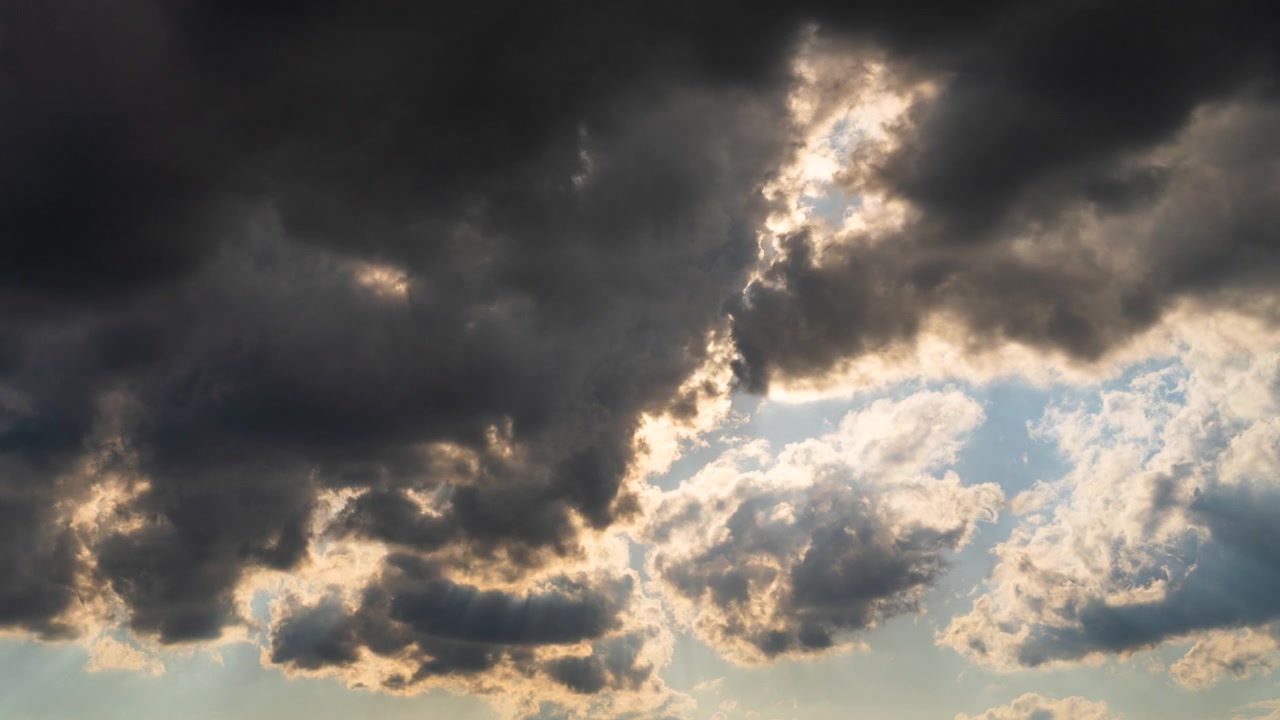 Sunset sky shining in orange tones behind dark moving cloud layers
