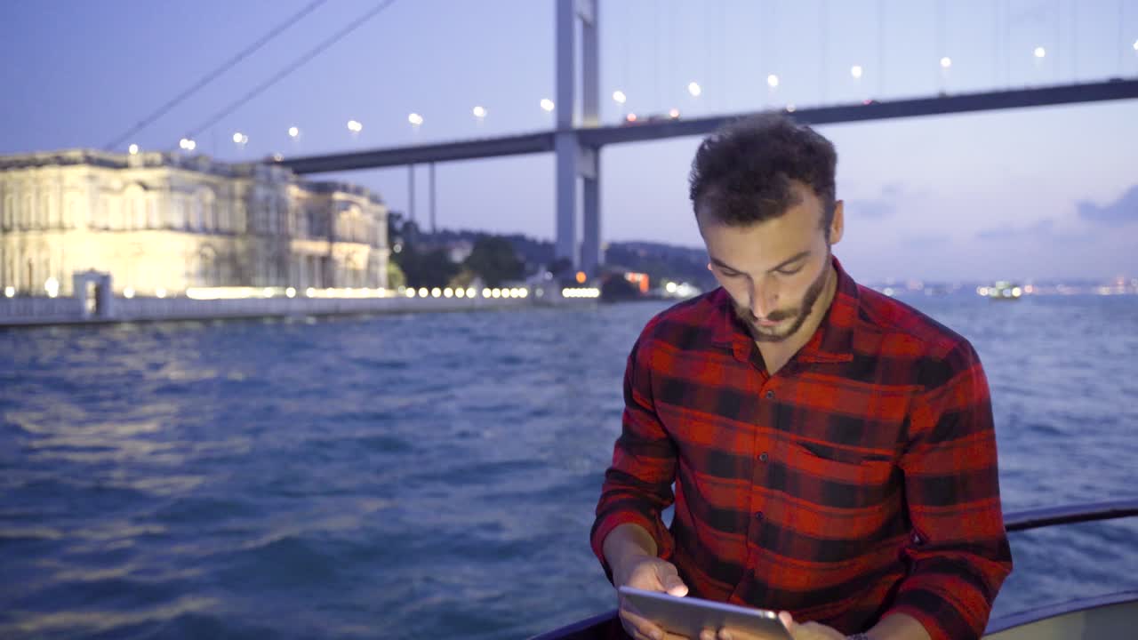 El hombre trabajando con una tableta en el ferry en el Bósforo