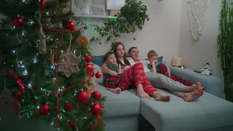 Family-Bonding-at-Christmas.-together-on-a-sofa-and-watching-TV-at-home-during-Christmas-holidays.-High-quality-4k-footage