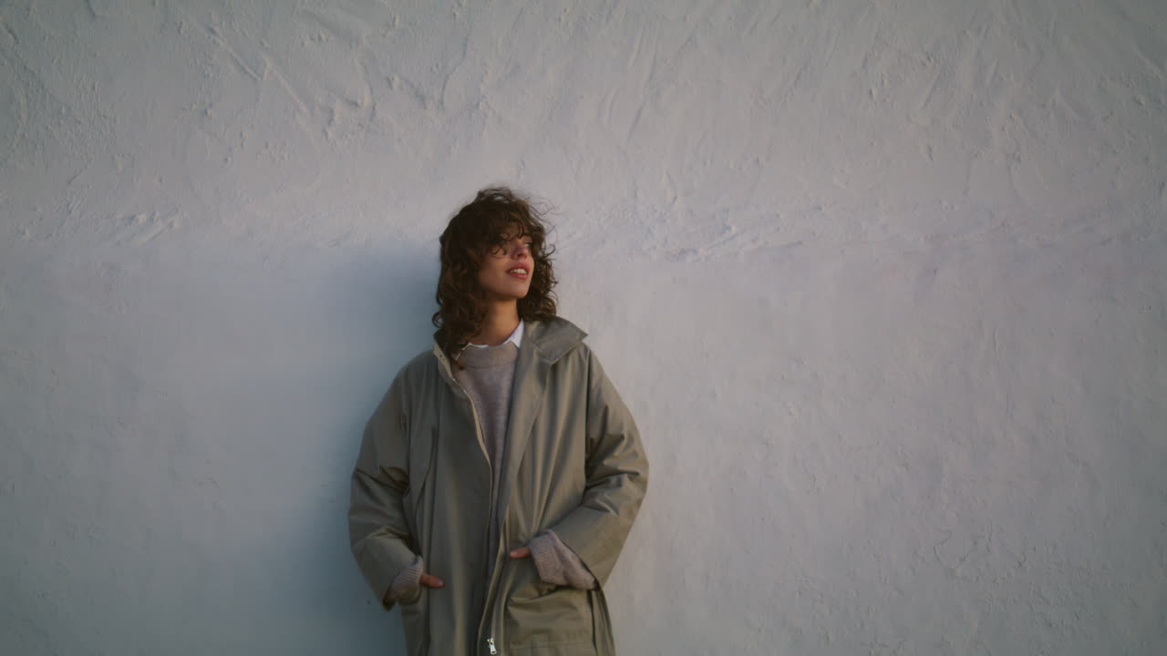 저녁에 도시 거리의 은 벽을 포즈하는 캐주얼 소녀. 수직 밀레니엄 기