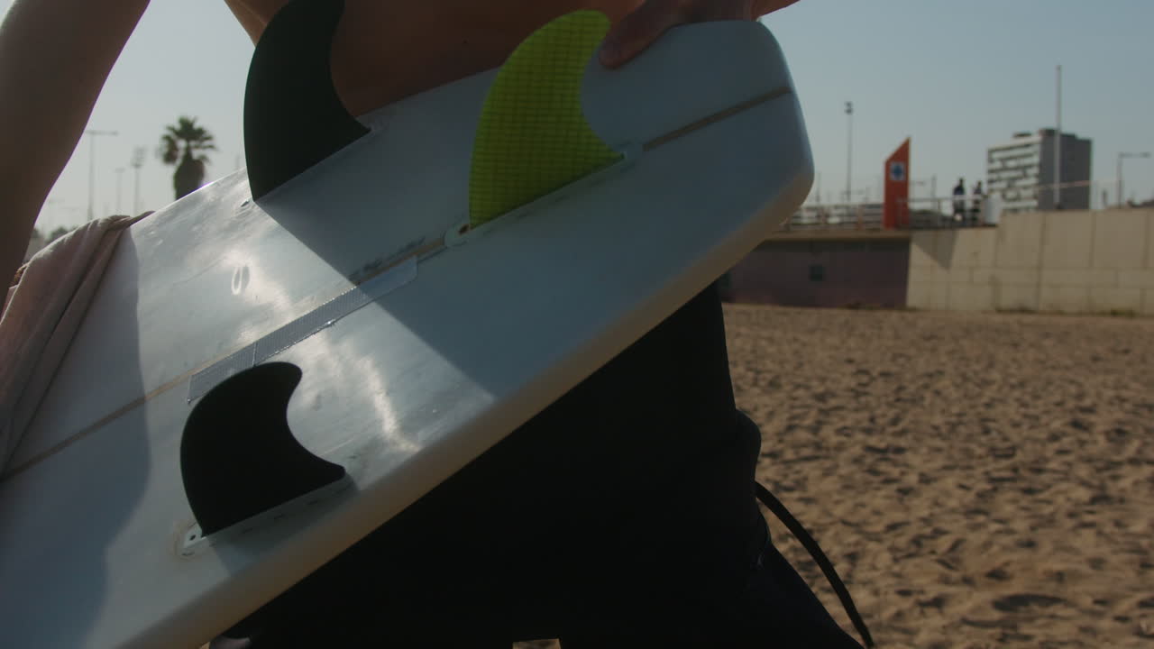 Surfer man walking to the beach at sunset preparing for surfing training and search for waves in Barcelona, spain, water, ocean exercise in sea with board, athletic male holiday or travel in vacation