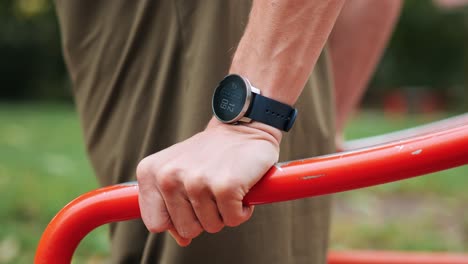 Man-trains-on-machine-in-public-park-monitors-his-training-session-with-smartwatch