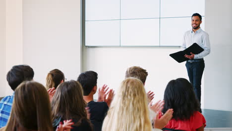 teacher giving presentation to high school class in front of screen