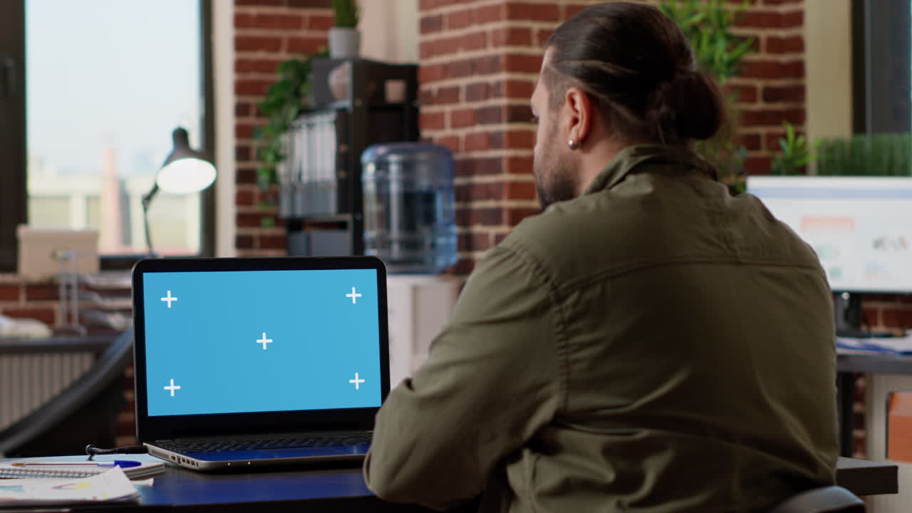 Office worker looking at greenscreen template on laptop