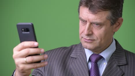 mature handsome businessman against green background