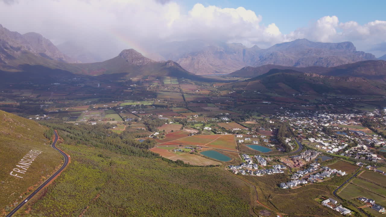 vuelo a lo largo del paso de franschhoek que muestra la ciudad, los viñedos en las granjas y las montañas