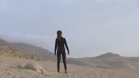 Toma-Cinematográfica-Desde-Atrás-De-Una-Mujer-De-Negro-Observando-El-Desierto-Con-Un-Cielo-Nublado