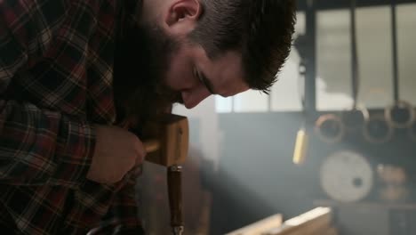 carpenter working with pouch in moody workshop