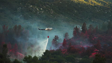 aerial fire fighting, helicopter dropping water from suspended bucket to battle wildfires in california, june 2020