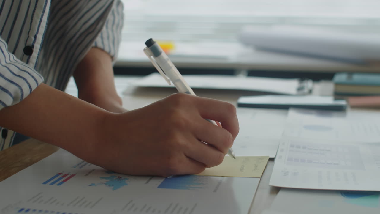 Hands of Project Manager Working with Charts and Documents at Table