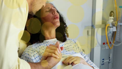 animation of yellow spots over caucasian man and biracial pregnant woman in labour