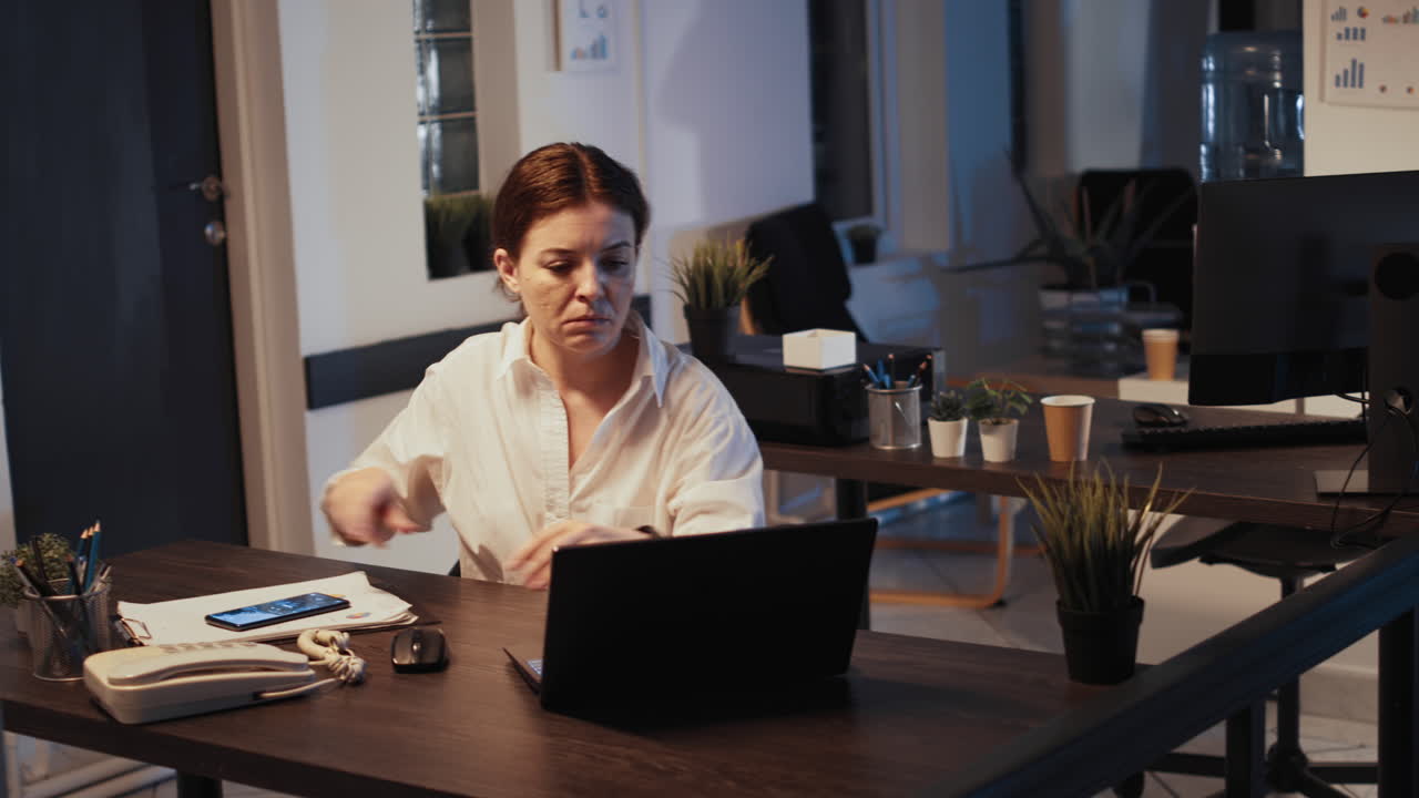 Kontormedarbejder, der arbejder på bærbar computer sent om aftenen