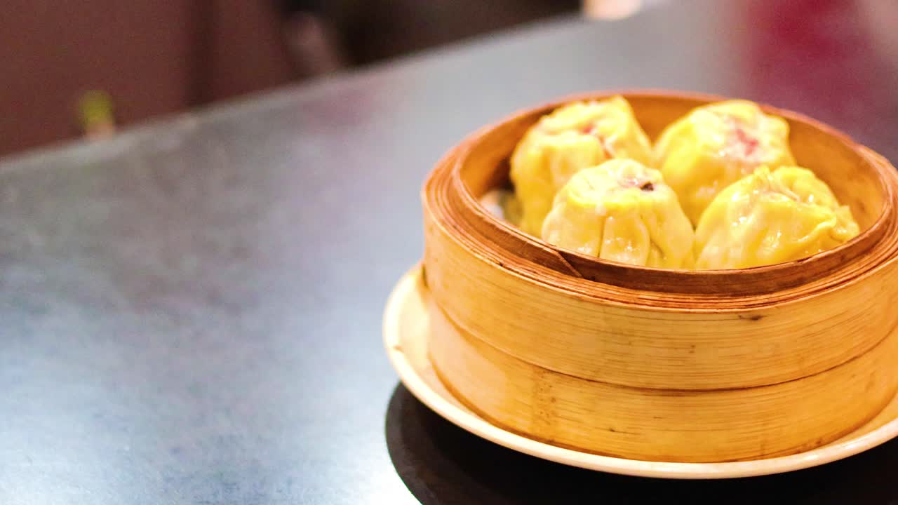 Tangan menyajikan siu mai di atas meja