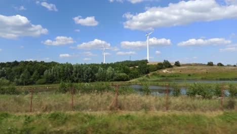 Aufnahme-Einer-Vorbeifahrenden-Windkraftanlage,-Die-In-Einem-Fahrzeug-Auf-Der-Straße-Erneuerbare-Energie-Erzeugt,-4k