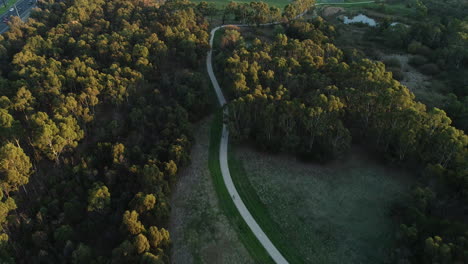 Bike-riders-following-along-nature-pathway-near-busy-highway-and-sporting-facilities