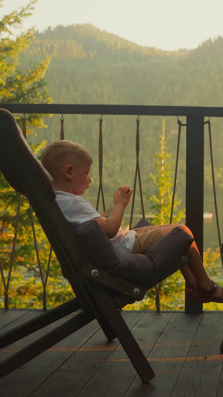 hermano y hermana envían mensajes usando teléfonos móviles modernos en el balcón con una vista impresionante. niños relajados tienen un gran tiempo rodeados de naturaleza indomable