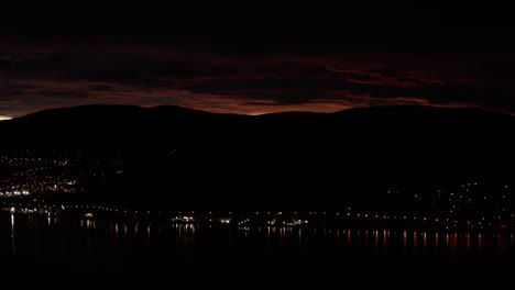 sunset in new zealand in a mountain with distant mountain-city light and red sky