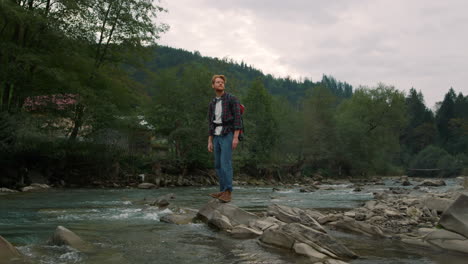 hiker standing on rocky shore of river