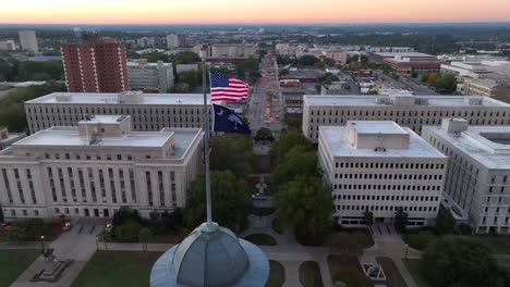 government buildings behind american and south carolina flags atop state house in columbia, sc