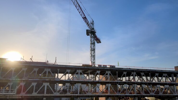 Sunset aerial arc shot of construction crane at building site in city