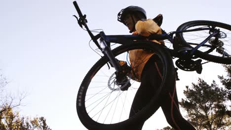 female mountain biker carrying bicycle in the forest