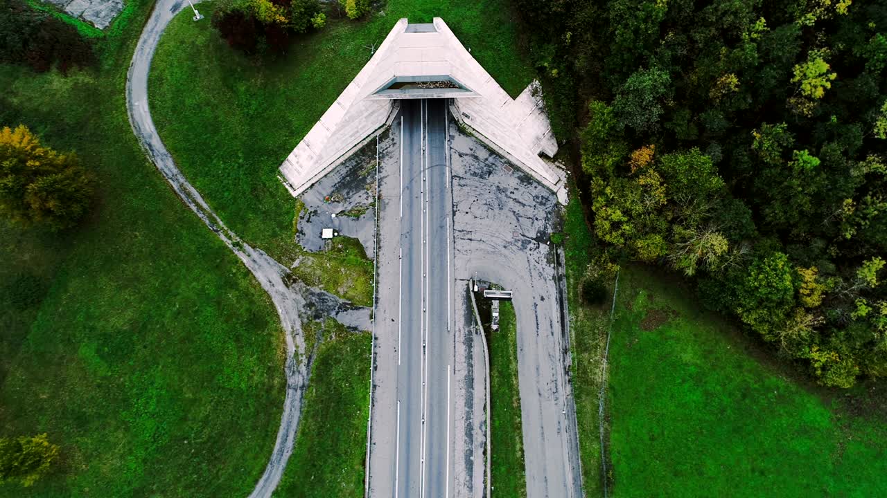 vista aérea sobre las carreteras que entran en un túnel en francia. sólo campos de hierba y árboles alrededor de las carreteras. coches y camiones conduciendo en las carreteras