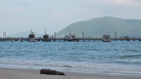 Vista-Panorámica-Del-Océano-Del-Nuevo-Muelle-Desde-La-Costa-Con-Montañas-De-Fondo-En-Con-Dao-En-Vietnam