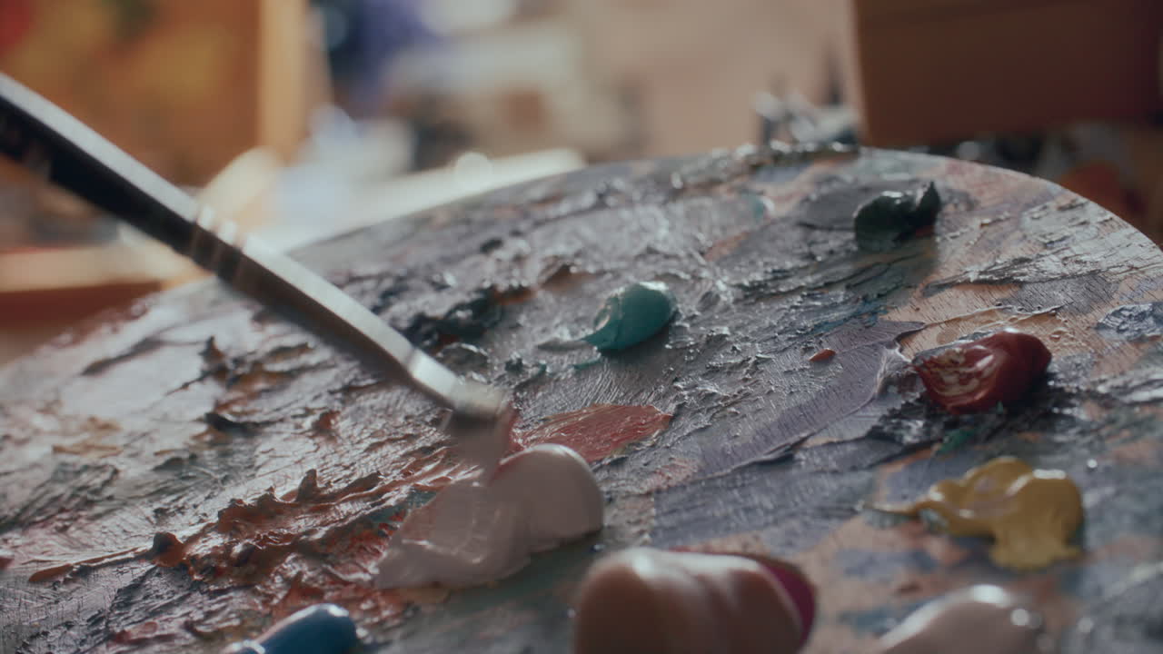 Primo piano di pittura a olio che si mescola su tavolozza texturizzata con un pennello.