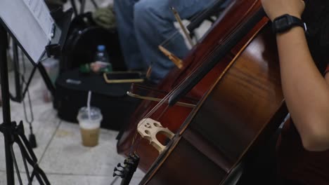 a cello players bows and stops for the next notes during rest in a piece as other players do the same, beginning orchestra