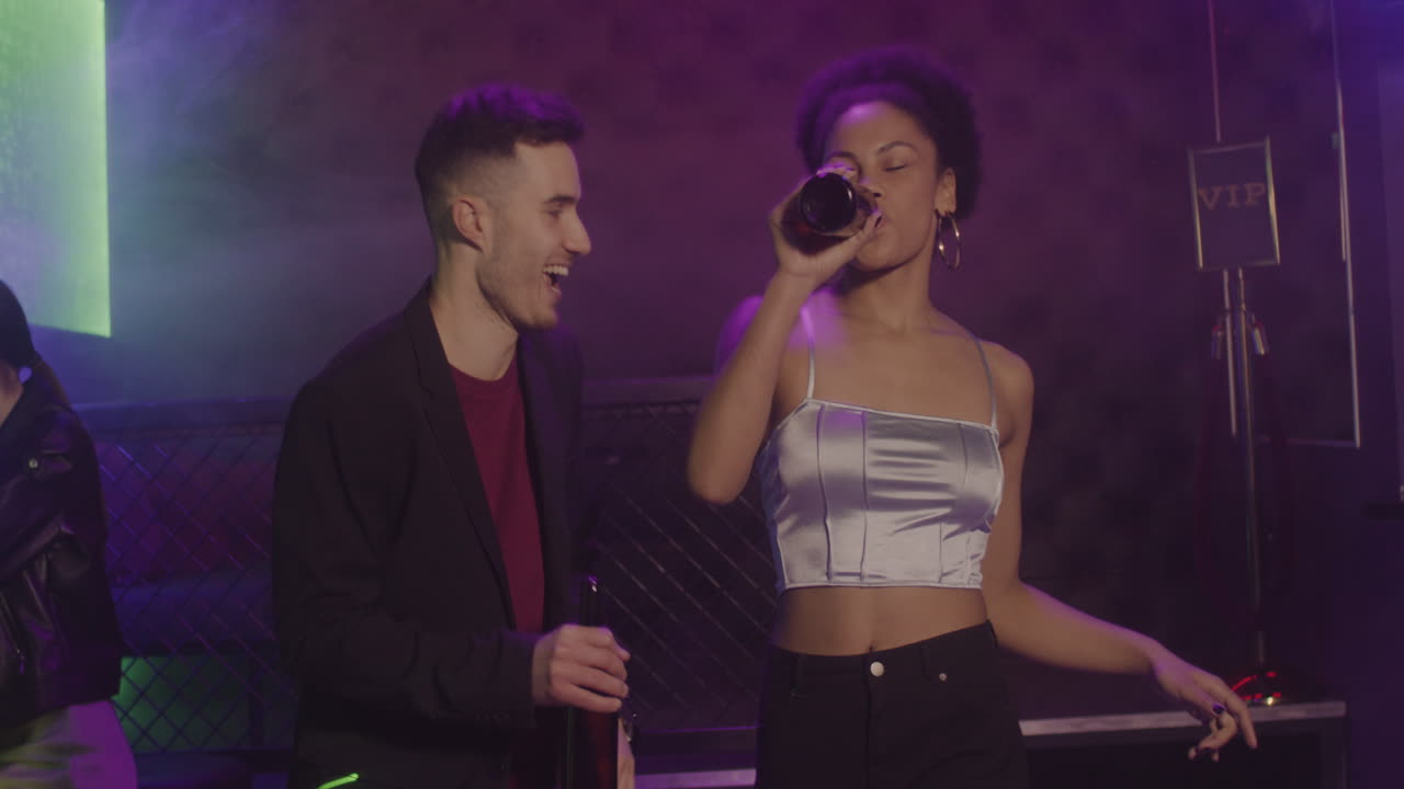 feliz pareja multiétnica bebiendo cerveza y bailando en la discoteca 4