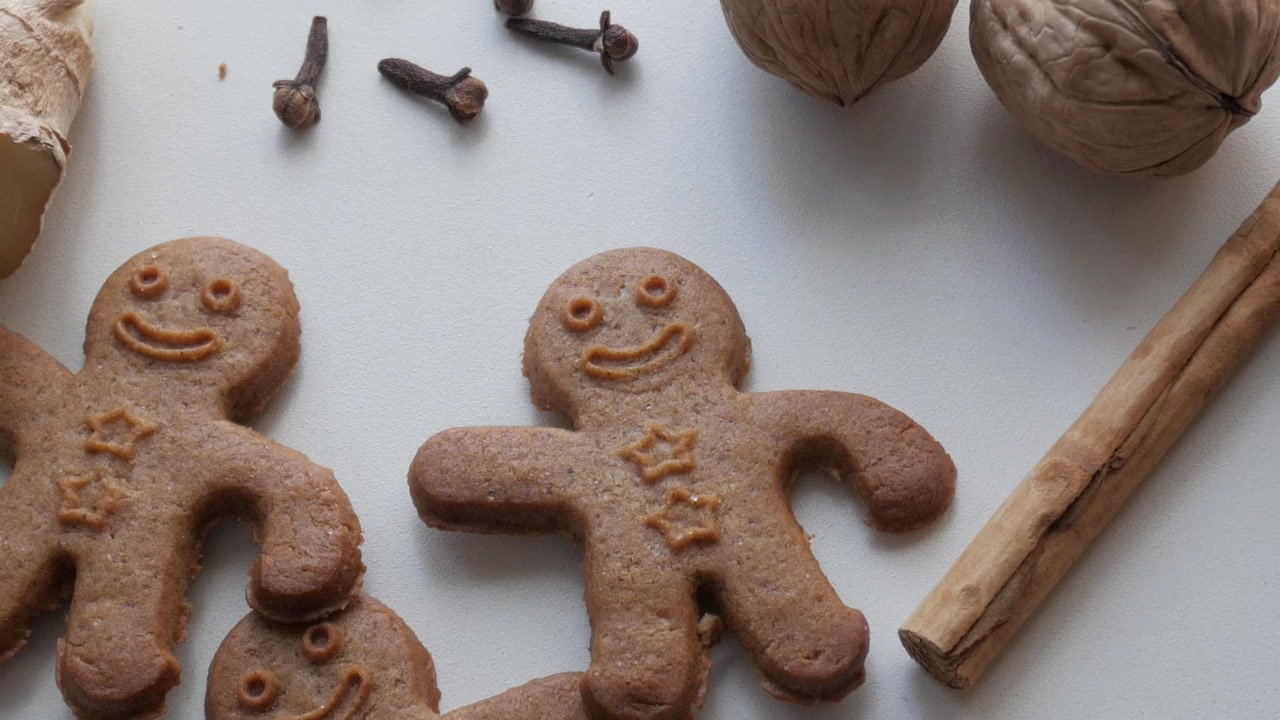 Biscotti di pan di zenzero a forma di omini felici, disposti su una superficie bianca.