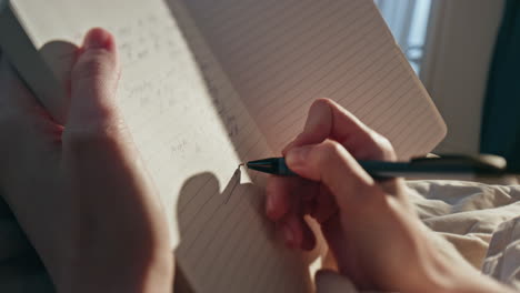 female hands writing diary in sunlight closeup. woman making notes in morning