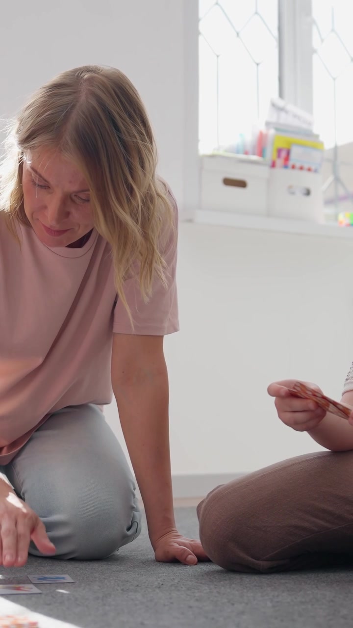 Matka i syn grający w edukacyjną grę karcianą na podłodze