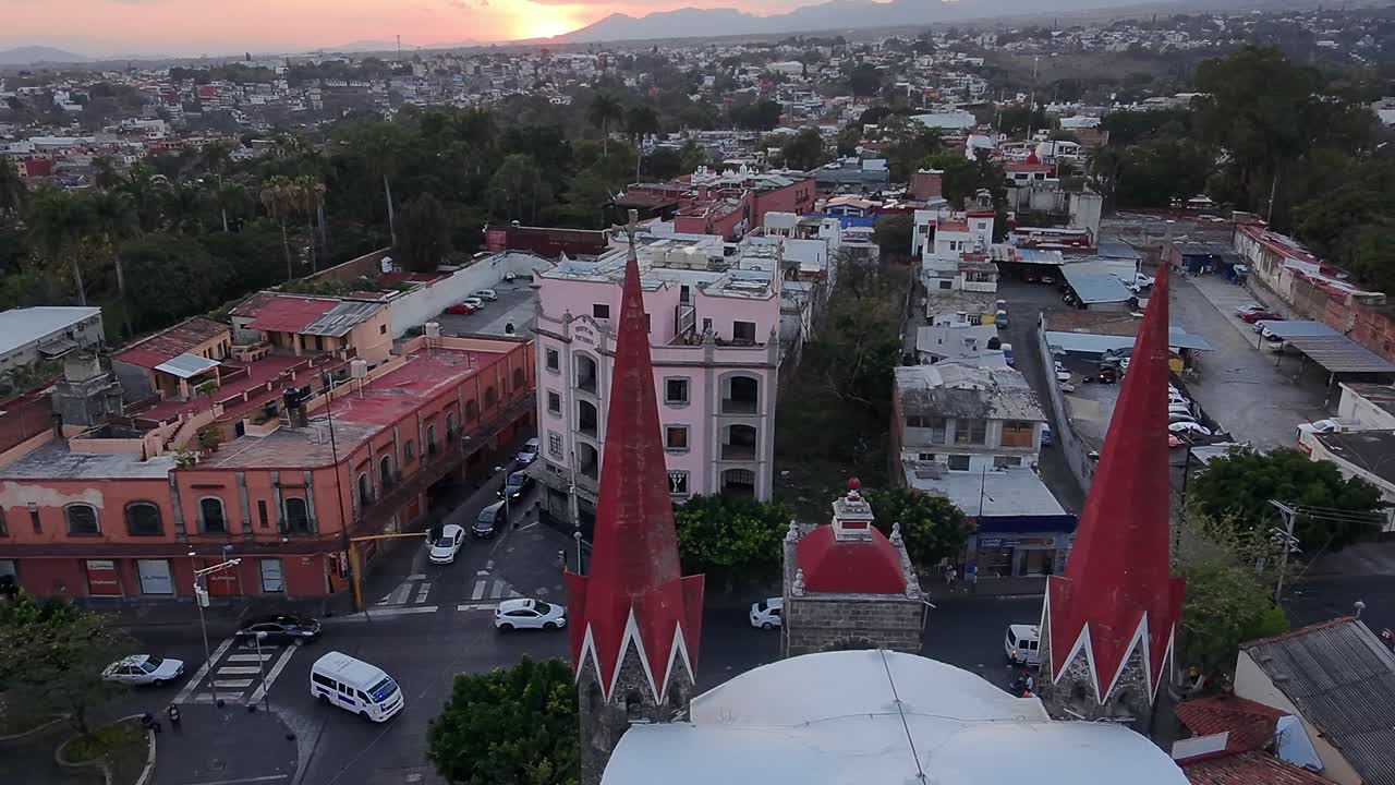 Aerial view capturing Cuernavaca city in Morelos, Mexico, featuring Calvario Church along with bustling streets, diverse buildings, vehicles, and lush vegetation in the vibrant urban landscape